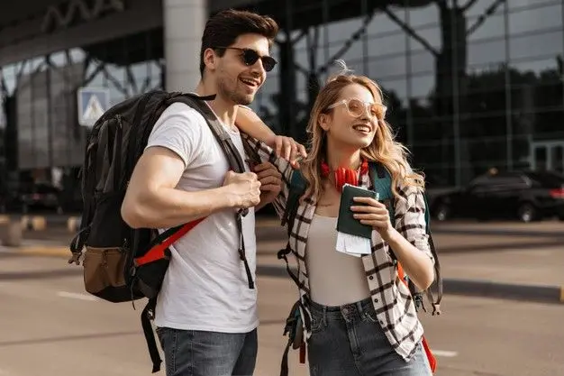 Smiling tourist couple with backpacks and passports arriving at the airport to take their private transportation in Costa Rica.